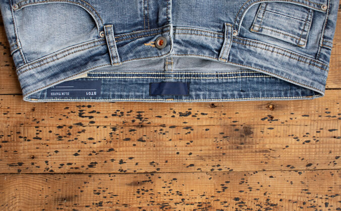 磨损蓝色牛仔裤的木质背景纹理牛仔布顶视图休闲衣服服装