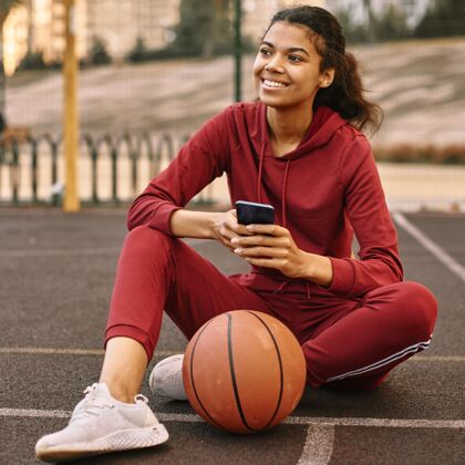 女子在篮球旁边看手机的女人篮球球年轻