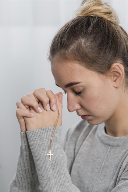 信仰年轻女子戴着十字架项链在家祈祷女人祈祷十字架